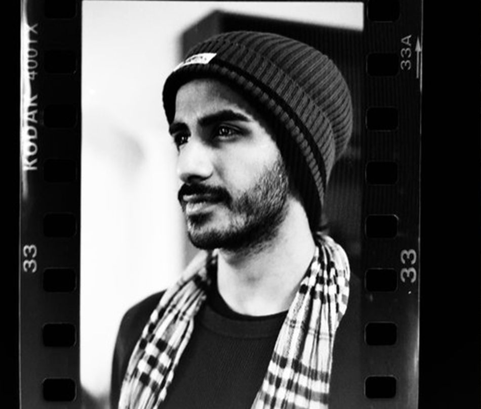 A photo of a photo of a person with a beard wearing a toque and a scarf.